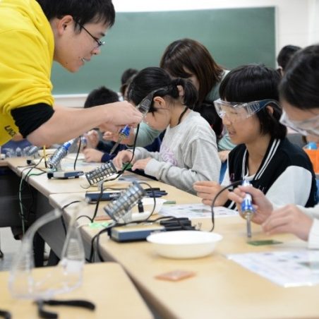 学生の手引きで工作体験をする来場者