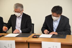 調印する入羽校長と岡﨑学部長