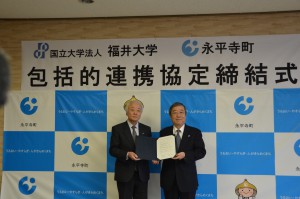 協定書を手にする松本文雄永平寺町（左）と眞弓光文学長（右）