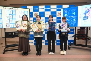 制作したカルタとクリアファイルを手にするサイバニクスのメンバー